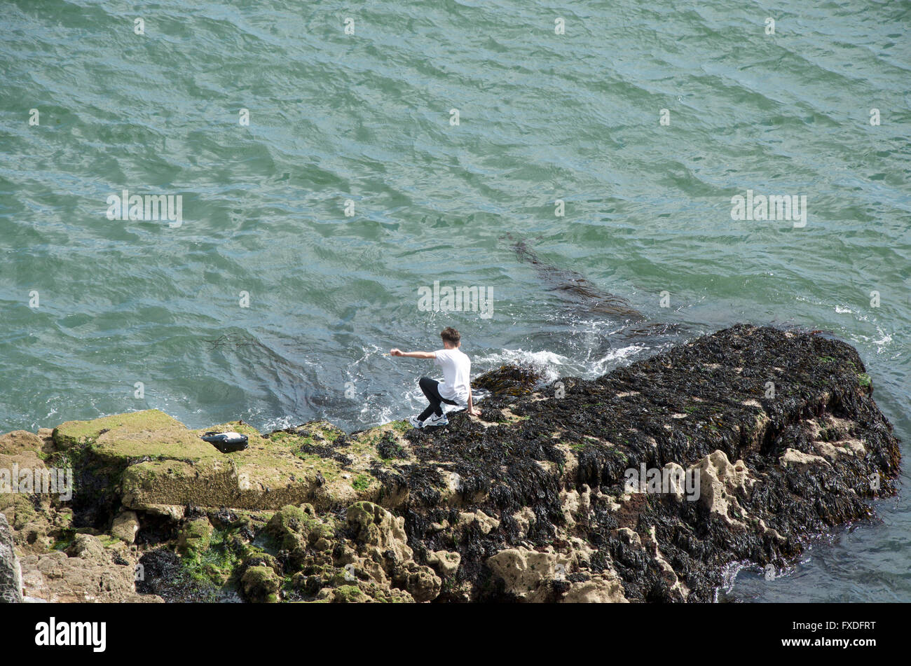 Un adolescent d'escalade sur rocher pontons près du Tinside Lido sur Plymouth Hoe Banque D'Images