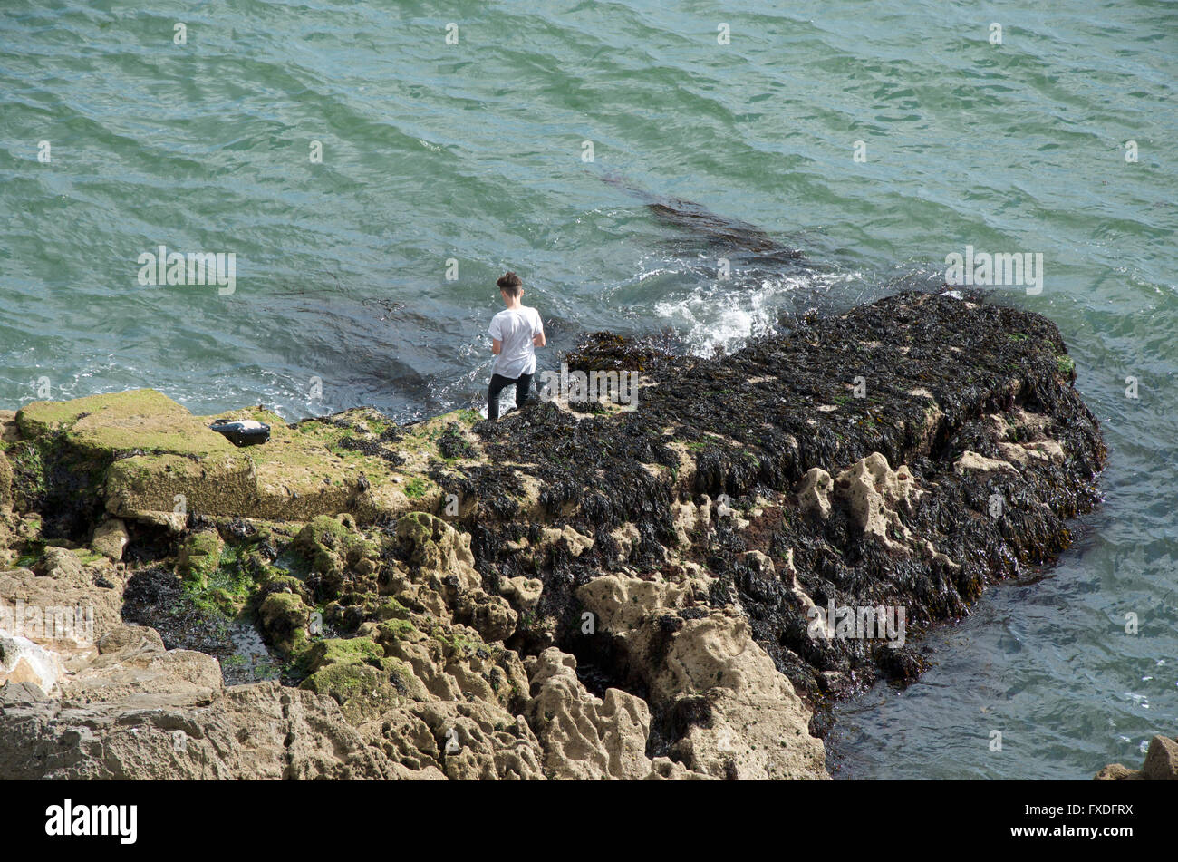 Un adolescent d'escalade sur rocher pontons près du Tinside Lido sur Plymouth Hoe Banque D'Images