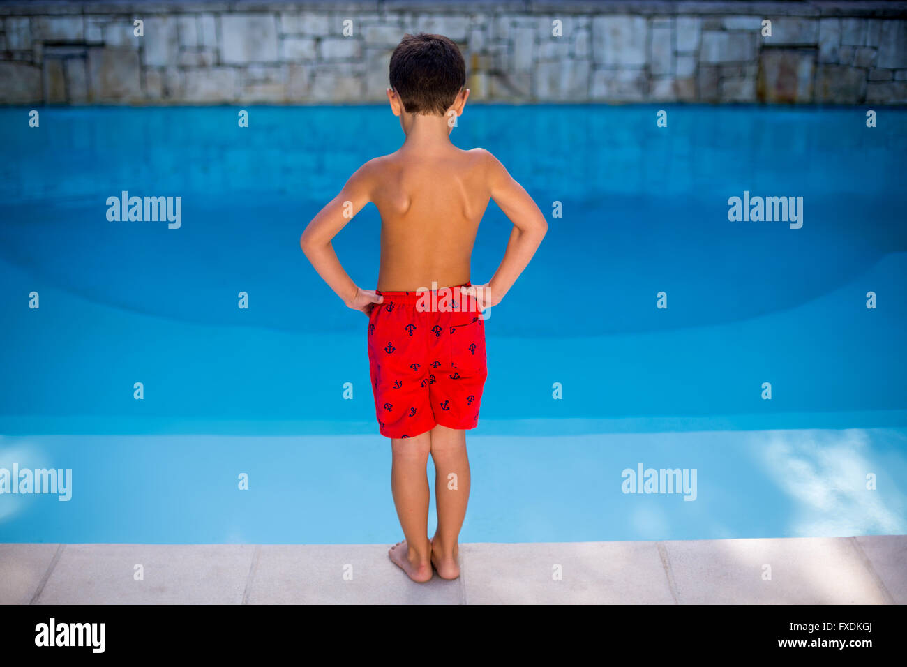 Shirtless boy standing in swimming pool Banque D'Images
