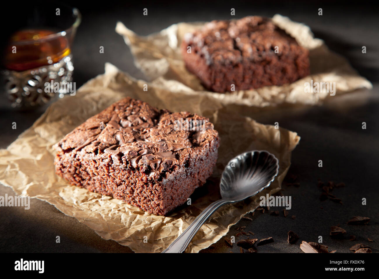 Deux brownies de sauce au chocolat sur papier avec cuillère et plateau Banque D'Images