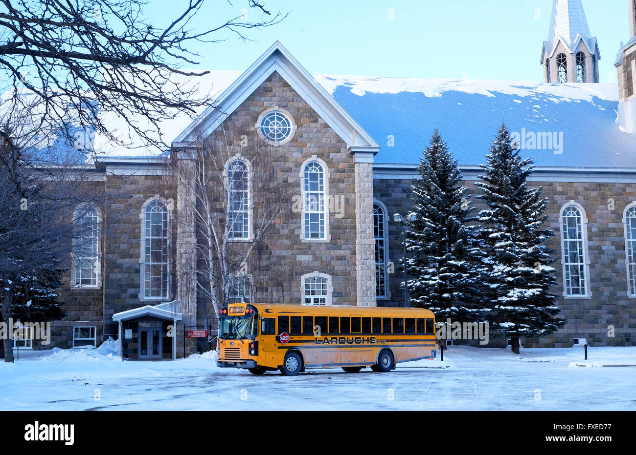 Vue d'une église en hiver avec un bus scolaire jaune au premier plan dans la ville de Québec, Québec, Canada. Banque D'Images