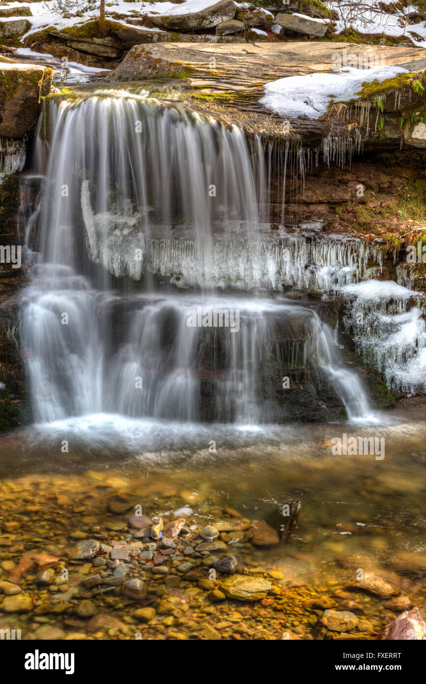 L'eau tombe doucement dans un bassin partiellement gelé plus de tuer de l'Ouest tombe dans les Catskills Mountains of New York. Banque D'Images