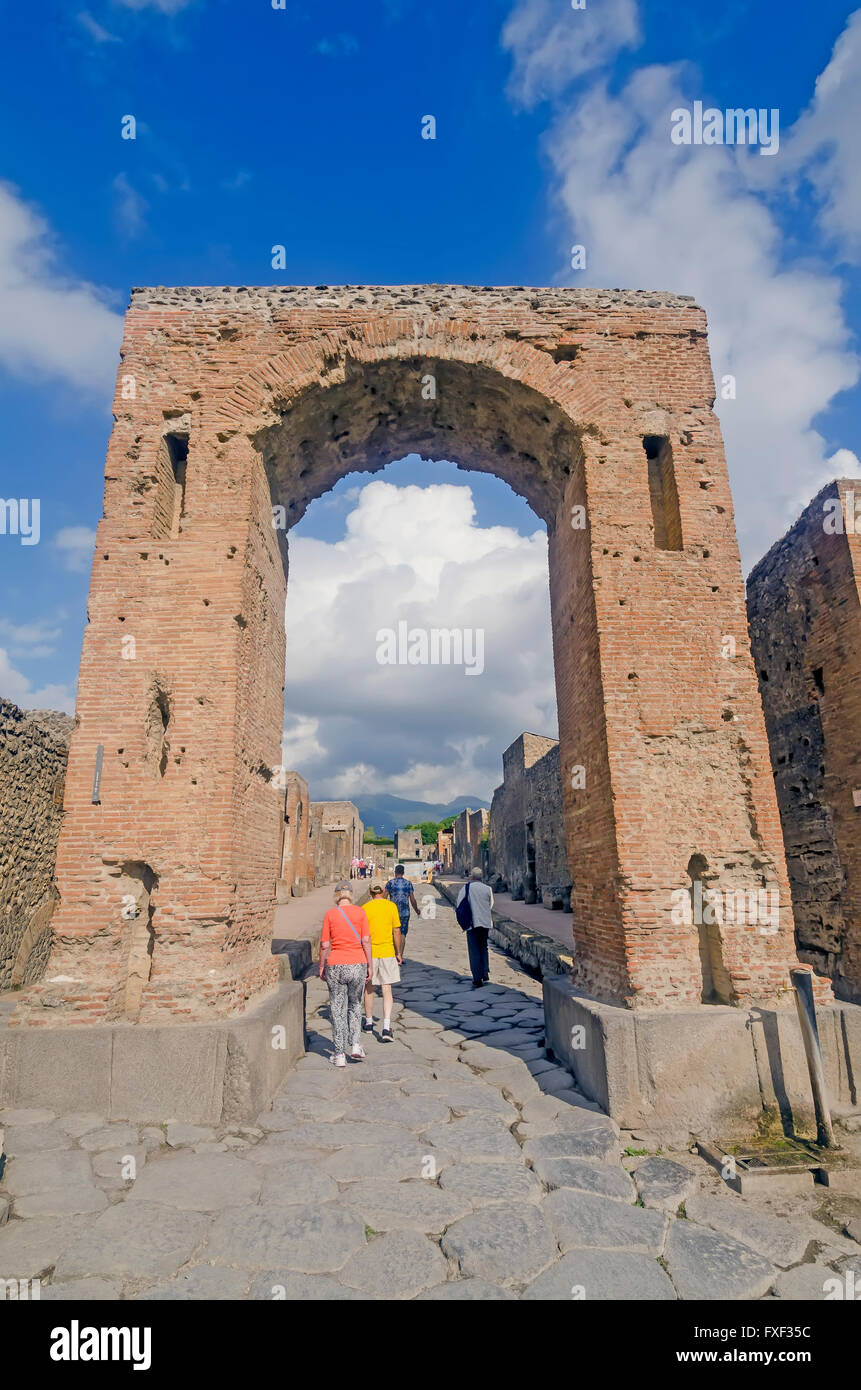 Toutists marche à travers Arch de Caligula au début de la Via Mercurio, le Vésuve en arrière-plan, Pompéi Italie Banque D'Images