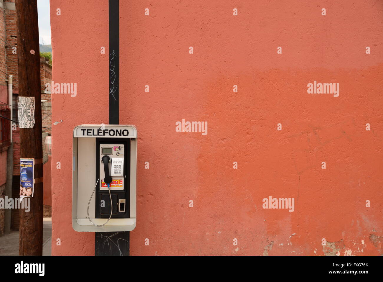 Peint en rouge et orange coin de rue avec une cabine téléphonique, l'espagnol. Guanajuato, Mexique. Banque D'Images