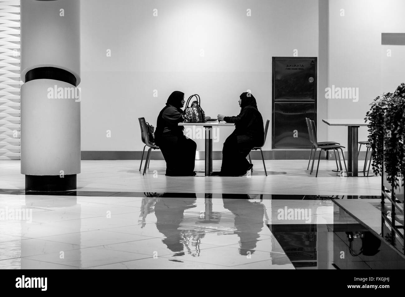 Les deux femmes en tenue traditionnelle de l'abaya assis à un café dans le centre commercial Avenues Oman, Muscat, Sultanat d'Oman Banque D'Images