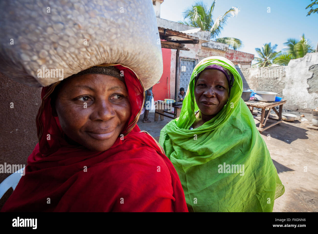 Le Mozambique,Femmes marchant dans la rue en robe de couleur et de voile, avec transport sur la tête. Banque D'Images