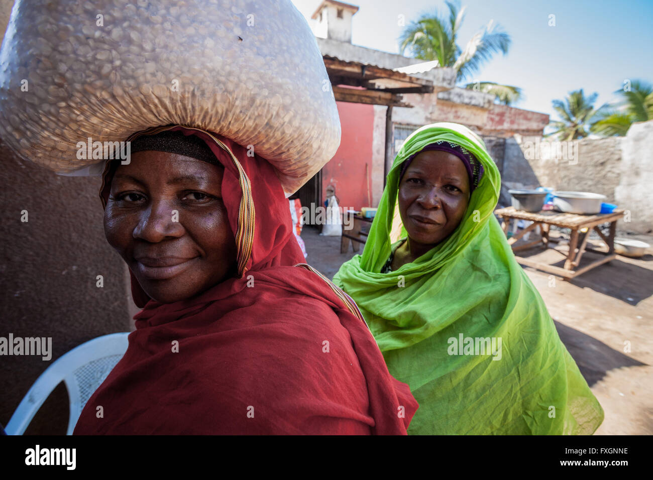 Le Mozambique,Femmes marchant dans la rue en robe de couleur et de voile, avec transport sur la tête. Banque D'Images