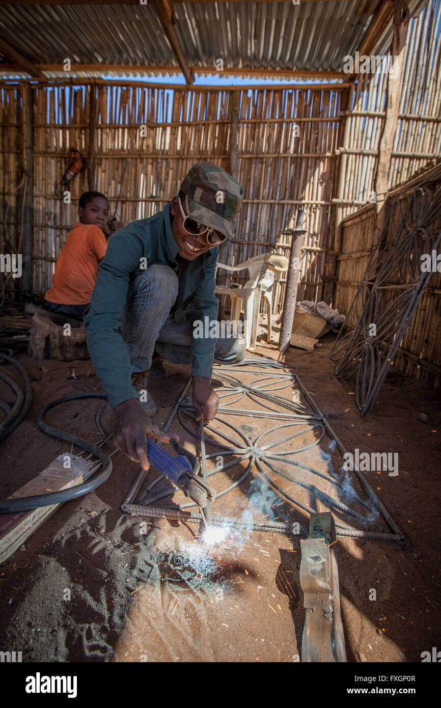 Au Mozambique, un homme et un enfant de soudage dans un atelier de serrurerie Banque D'Images