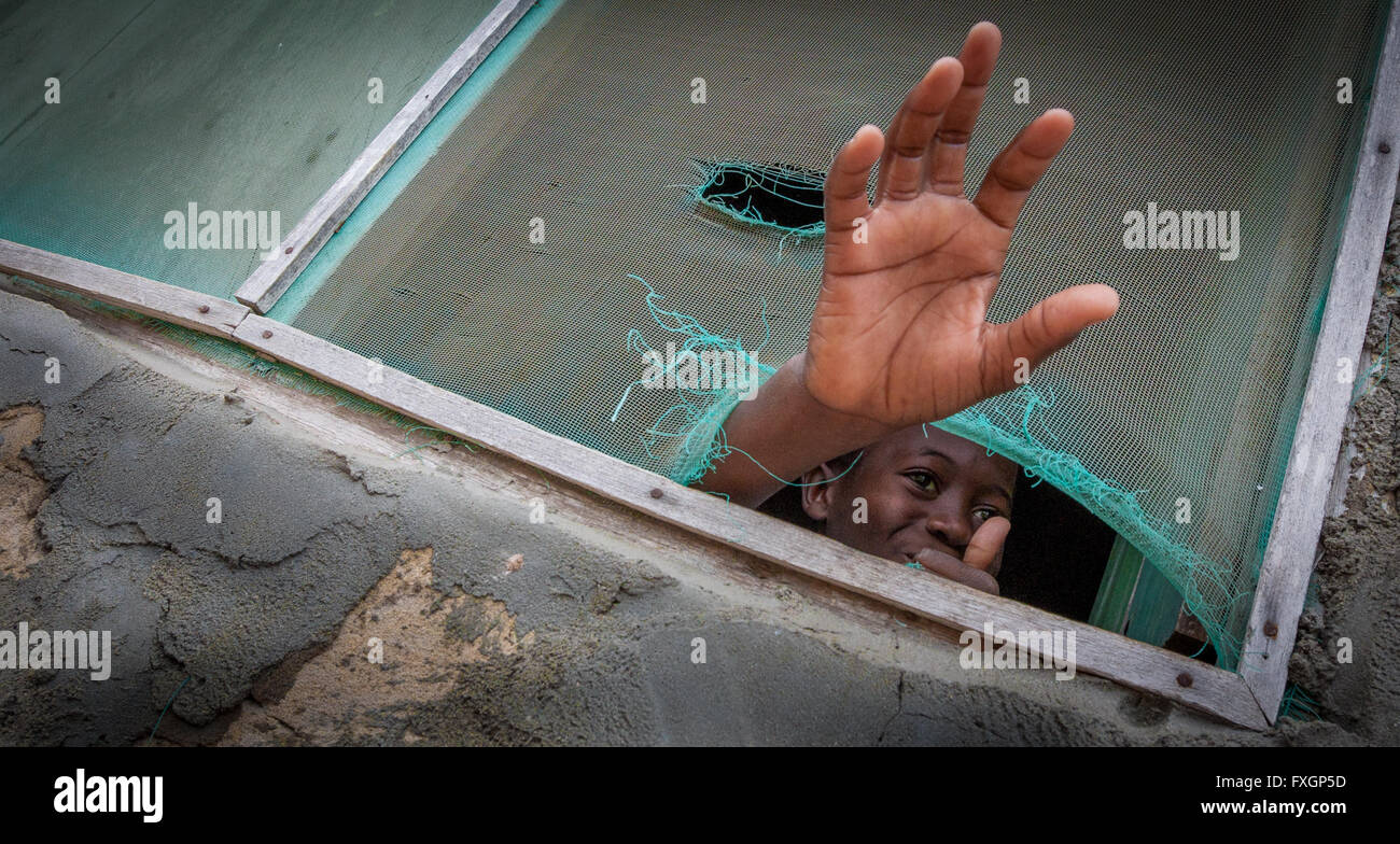 Le Mozambique,un garçon est en train de dire bonjour avec la main à partir de la fenêtre. Banque D'Images