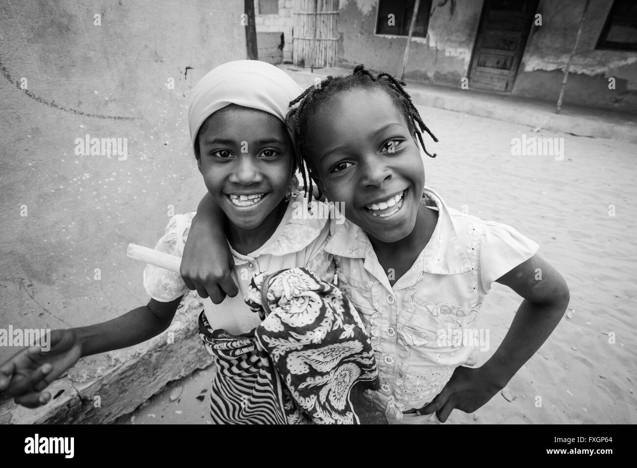Le Mozambique, deux filles l'amitié de sourire et de poser dans une accolade, noir et blanc, B&W. Banque D'Images