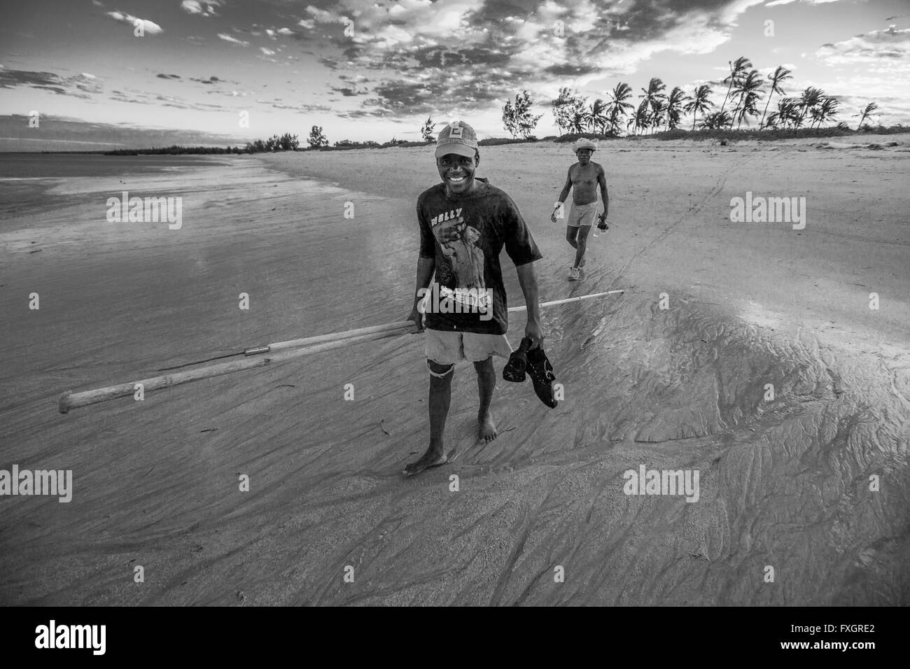 Au Mozambique, les pêcheurs sur la plage blanche au coucher du soleil avec la canne à pêche, noir et blanc, B&W. Banque D'Images