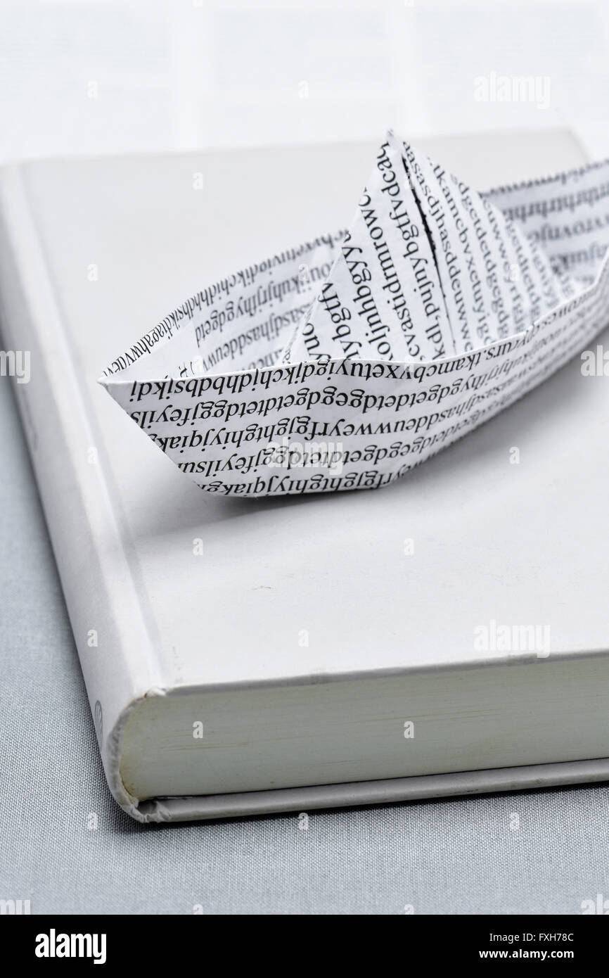 Libre d'un bateau de papier, fait avec un papier imprimé avec des mots non-sens, sur un livre Banque D'Images