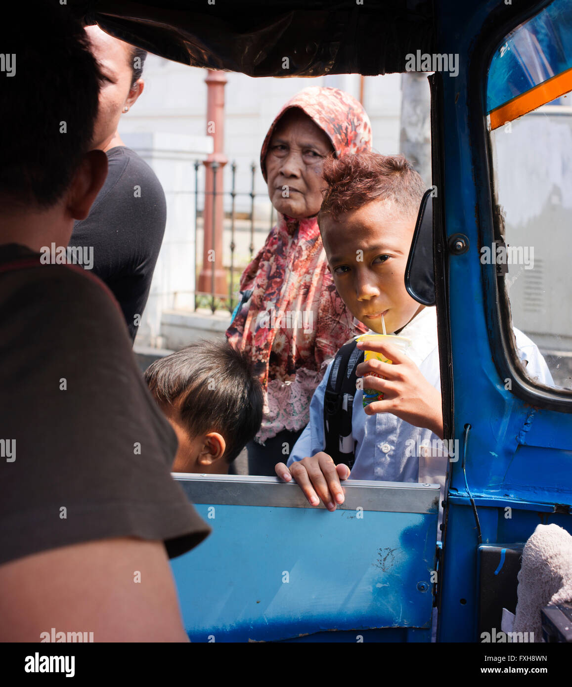 Les enfants et vieille femme vu depuis un tuk tuk utilisés pour le transport à Batavia, la vieille ville de Jakarta. Banque D'Images