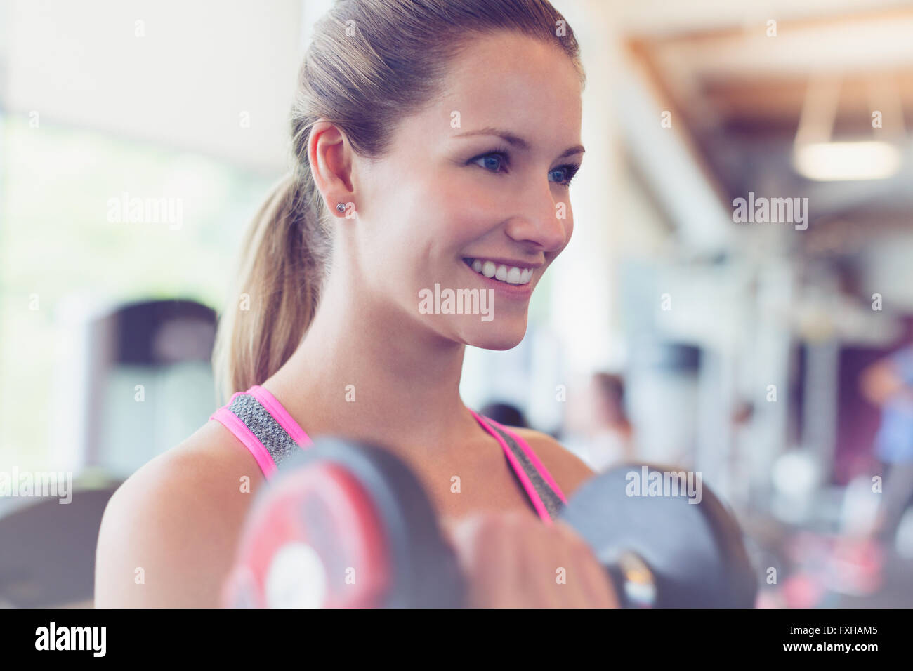 Close up smiling woman doing biceps haltère at gym Banque D'Images