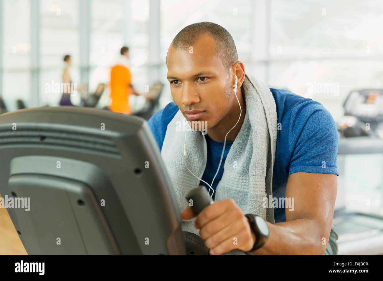 L'accent man riding exercise bike at gym Banque D'Images