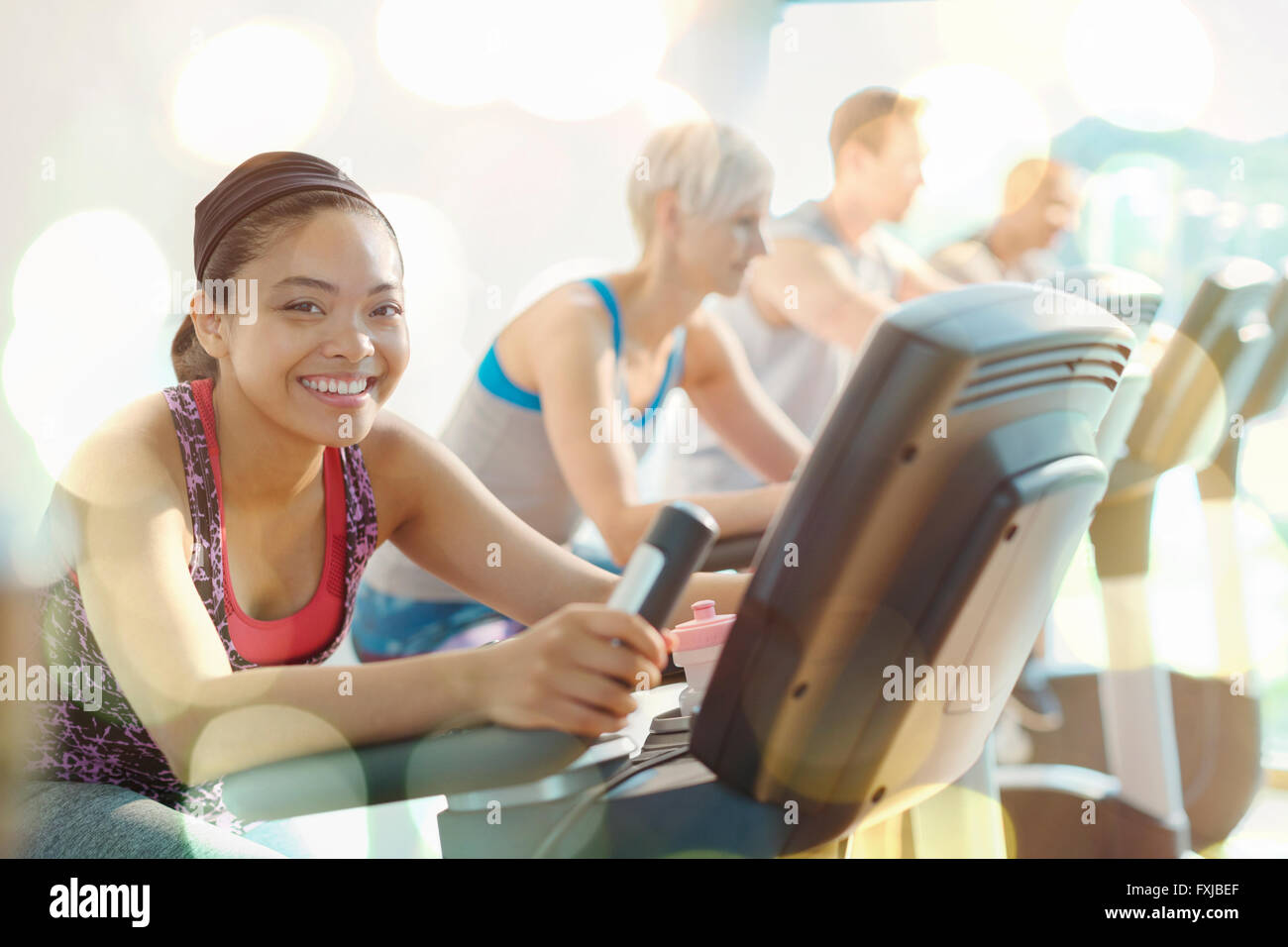 Portrait of smiling woman riding exercise bike at gym Banque D'Images