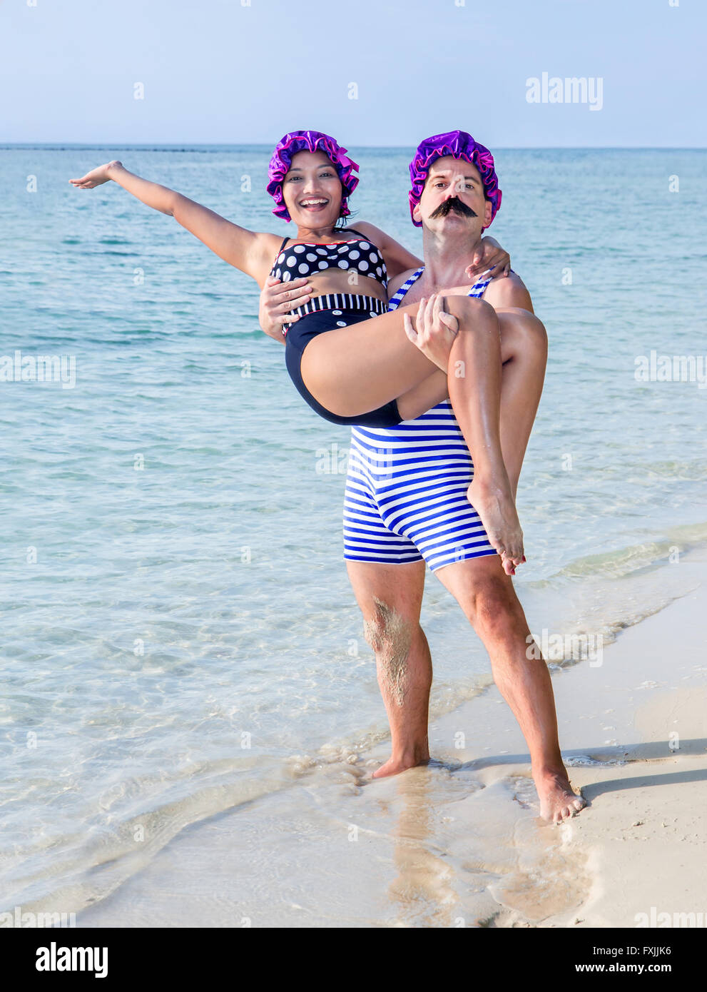 L'homme en maillot tenant dans ses bras une femme en maillot sur la plage mer Banque D'Images