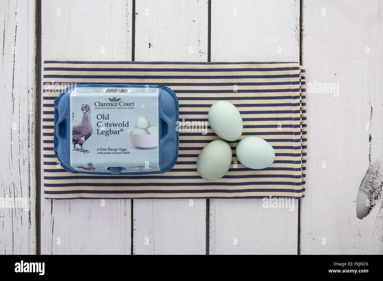 Cotswold vieux Legbar des œufs avec des coquilles de couleur pastel dans une boîte sur une serviette à rayures bleues et blanches sur la table rustique Banque D'Images