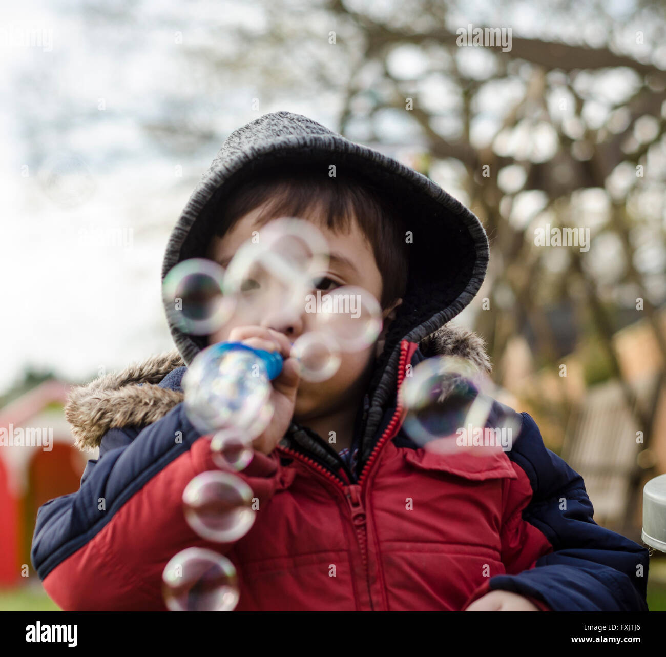 Un jeune garçon s'amusant à l'extérieur de faire des bulles. Banque D'Images