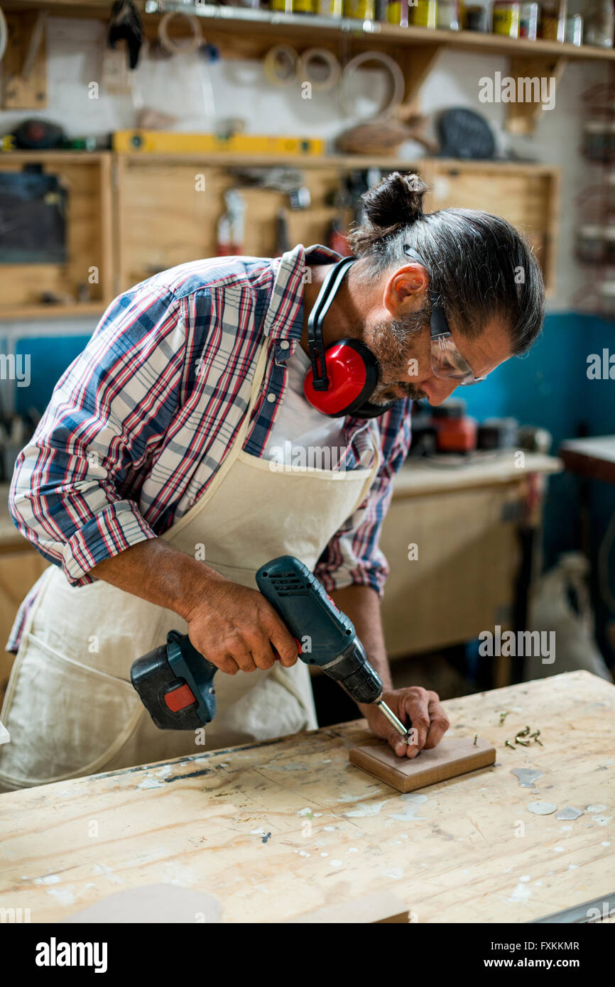 Carpenter de percer un trou dans une planche en bois Banque D'Images