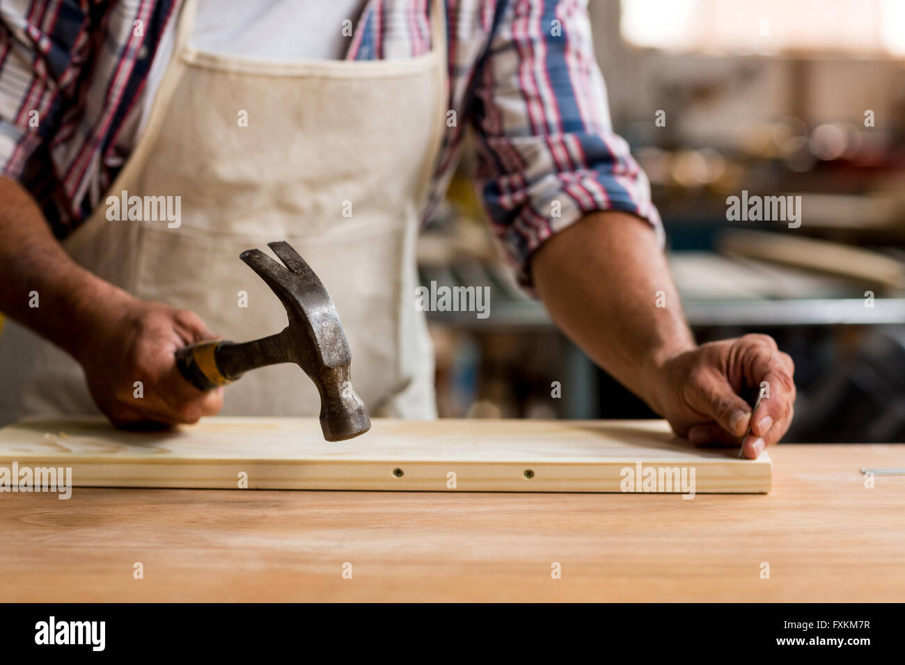 Carpenter à l'aide d'un marteau sur le bois Banque D'Images