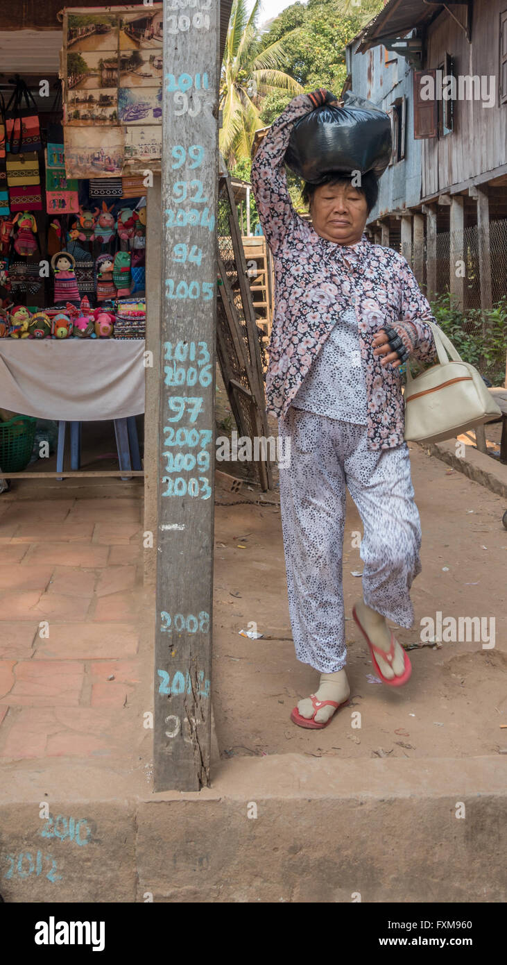 Marqueur sur une maison sur pilotis montrant les niveaux d'eau des crues à Chau Doc, au fil des années avec une personne portant un sac sur sa tête, Delta du Mekong, Vietnam Banque D'Images