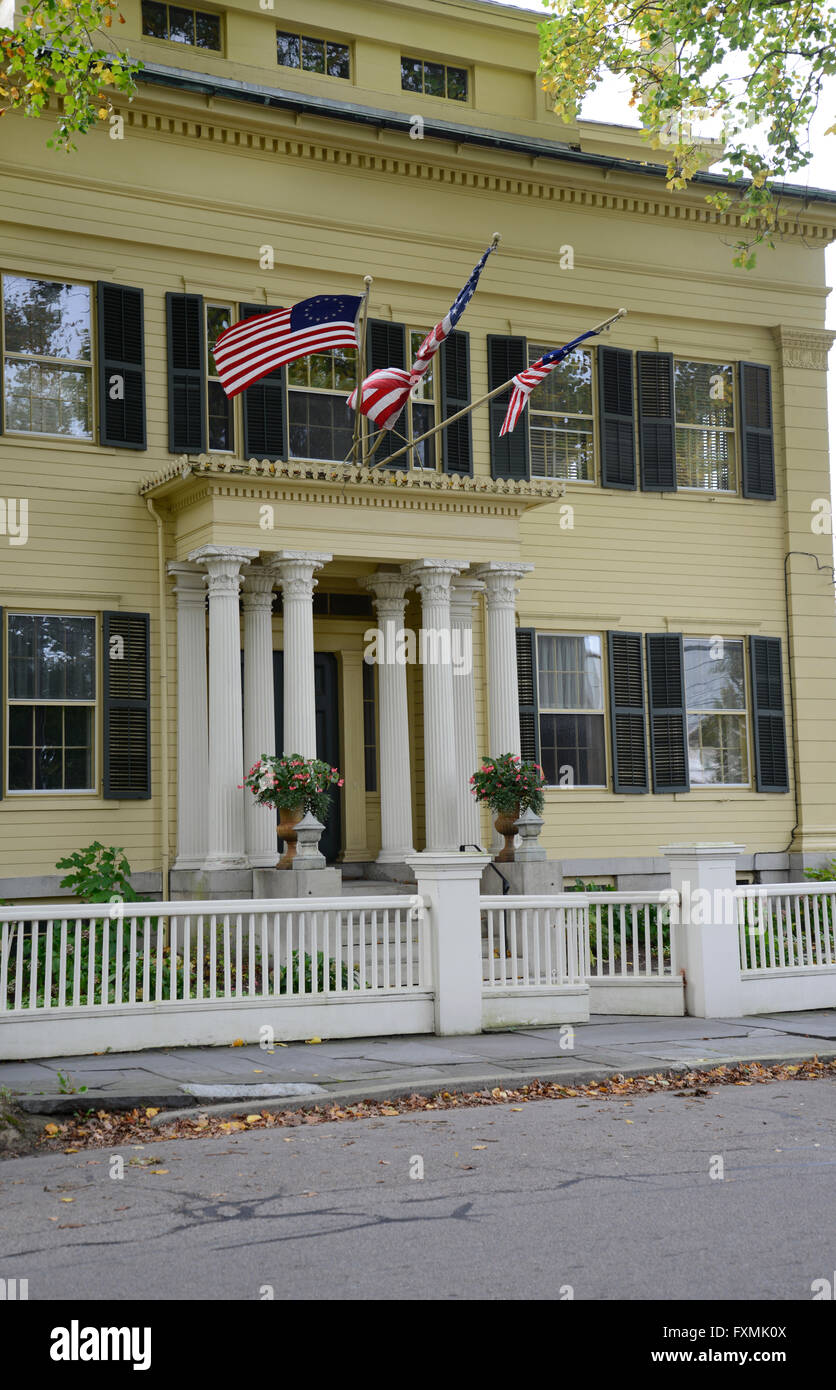 Extérieur d'une maison de style fédéral jaune de Stonington Connecticut. La maison a trois volets, noir et un drapeau américain whi Banque D'Images