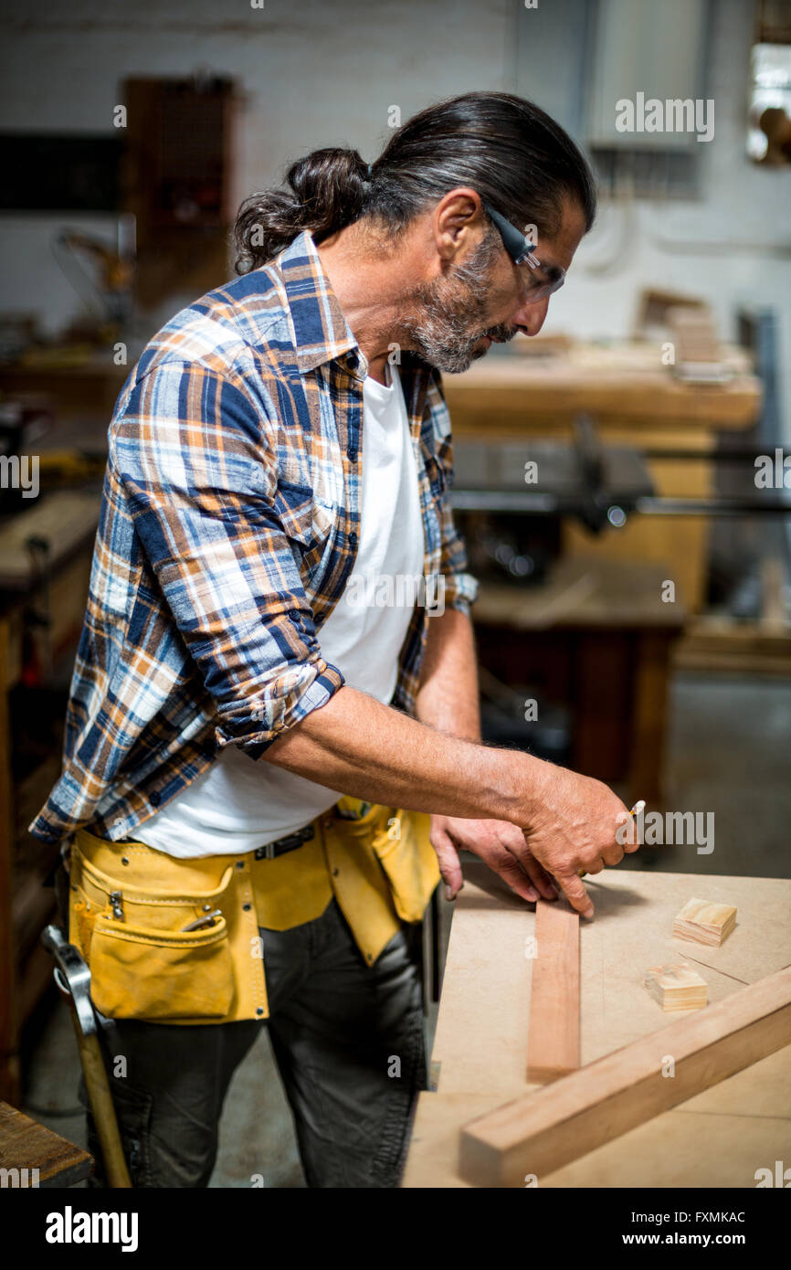 Carpenter marquage sur planche en bois avec un crayon Banque D'Images