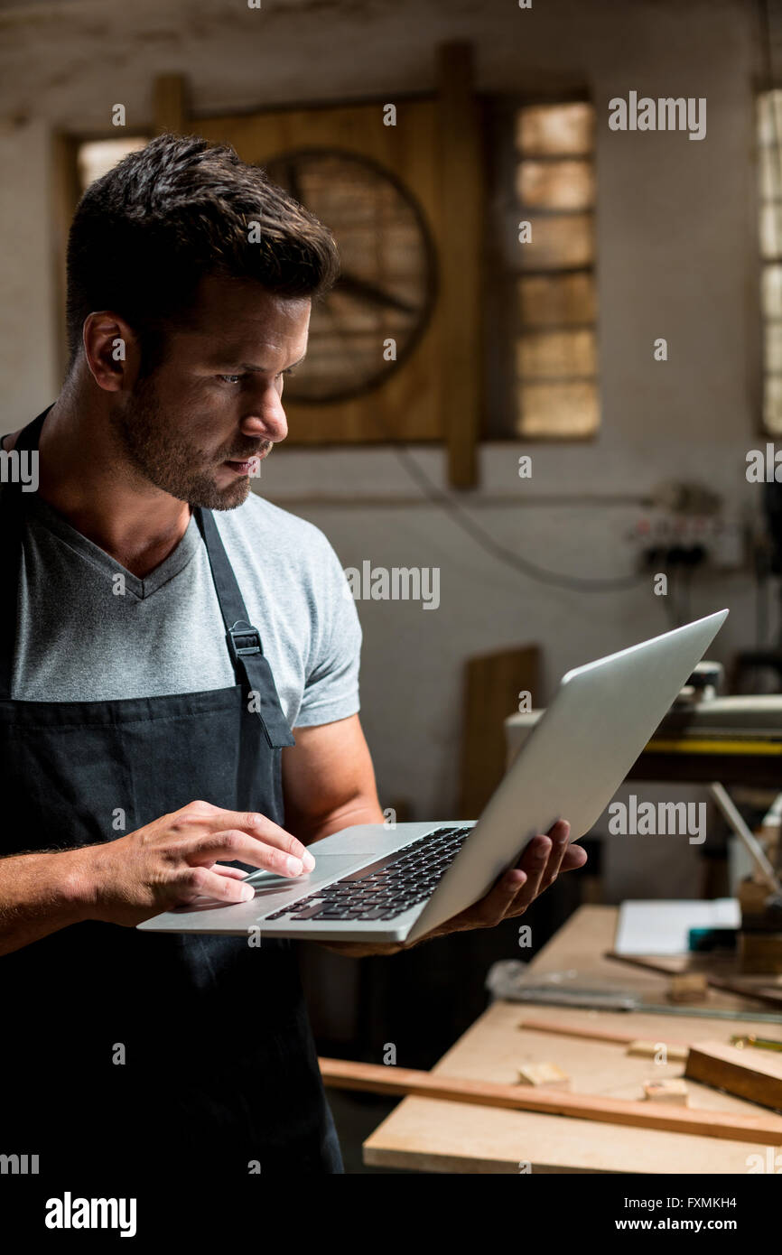 Carpenter using laptop in workshop Banque D'Images