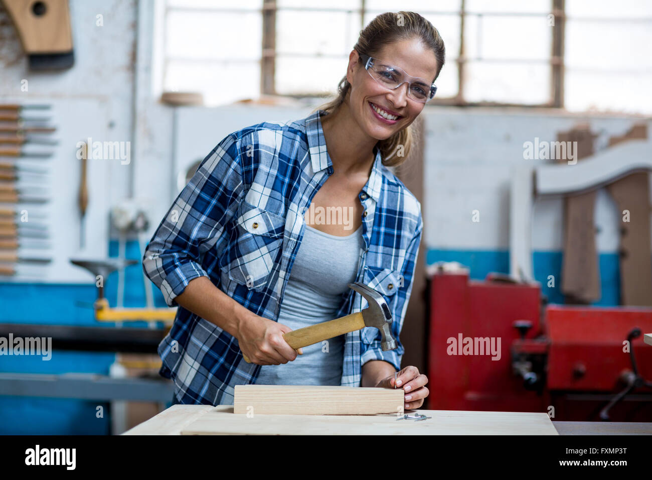 Femme tenant un marteau de charpentier à conduire des clous dans une planche en bois Banque D'Images