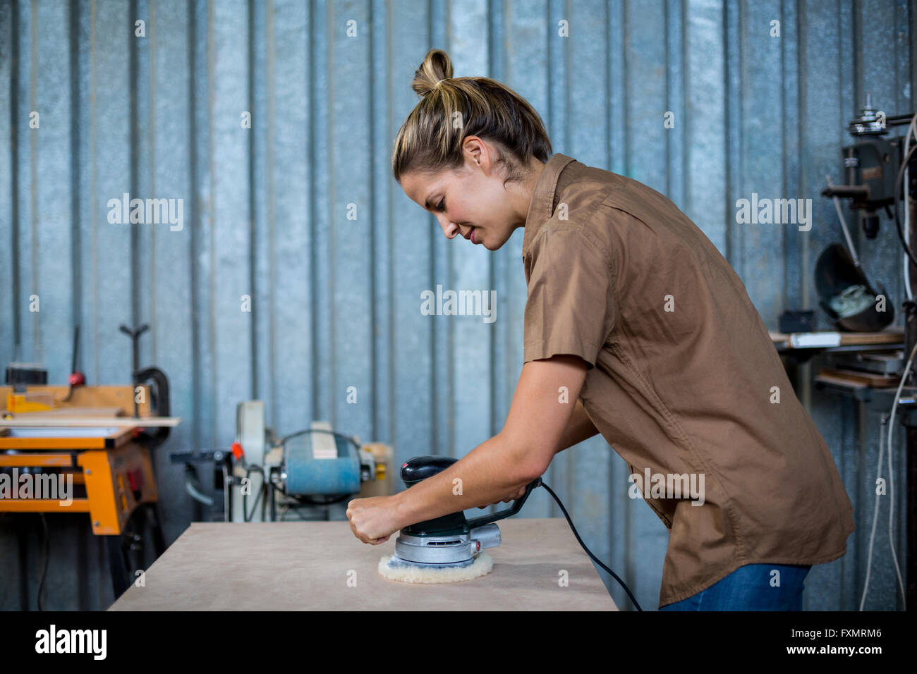Female carpenter polissage d'un planche en bois avec la machine de polissage Banque D'Images