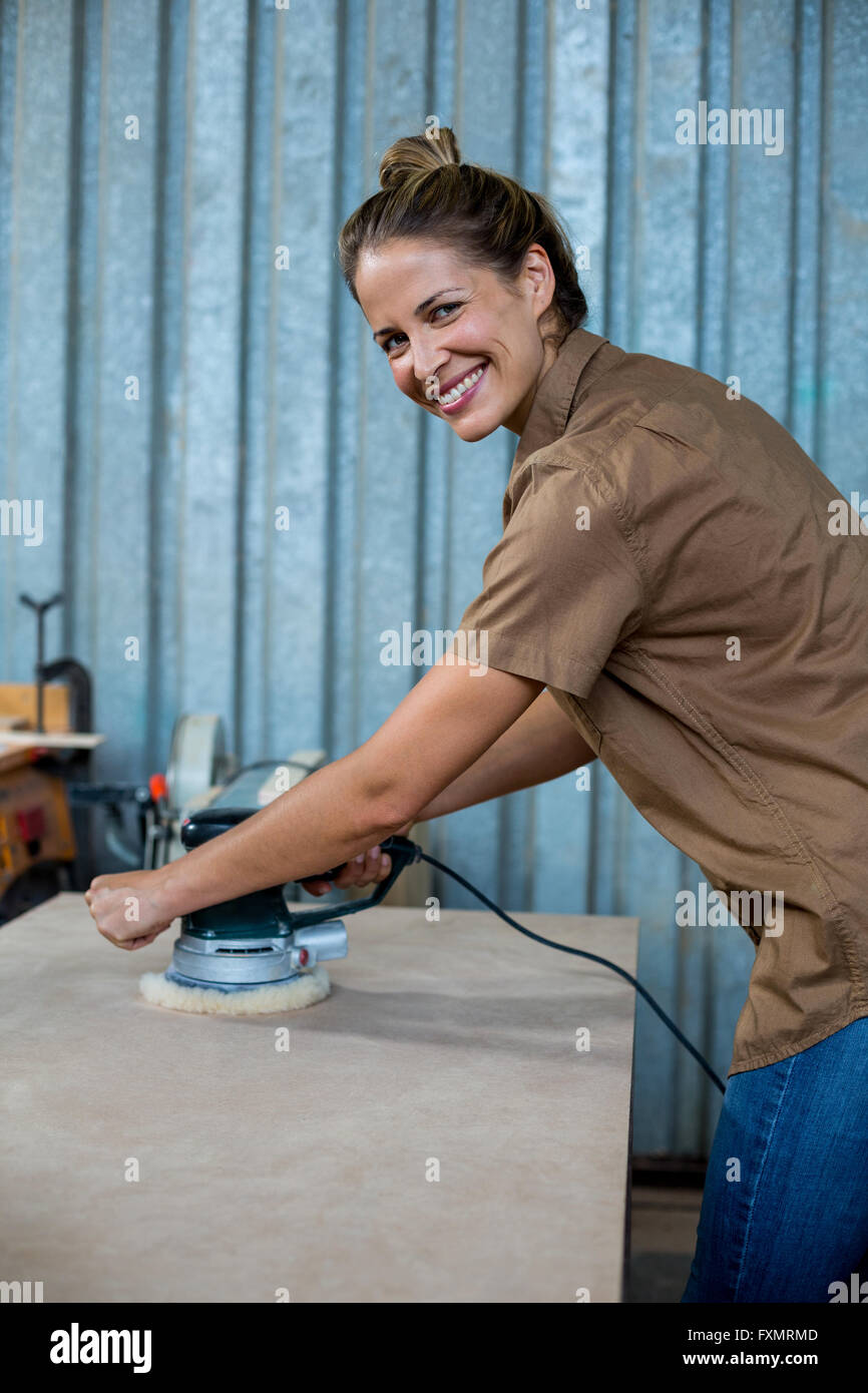 Female carpenter polissage d'un planche en bois avec la machine de polissage Banque D'Images