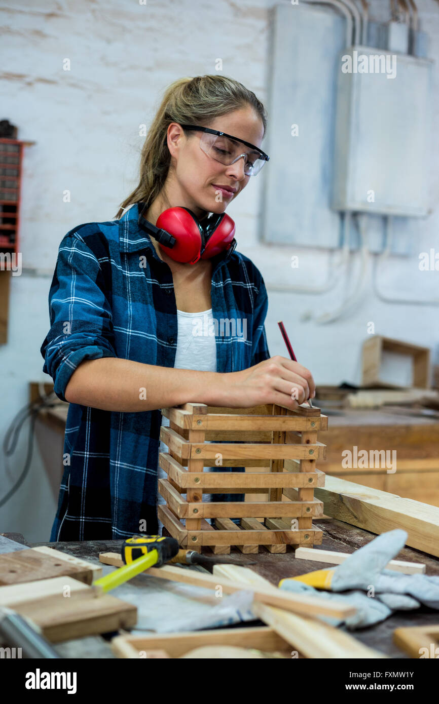 Female carpenter marquage sur planche en bois avec un crayon Banque D'Images