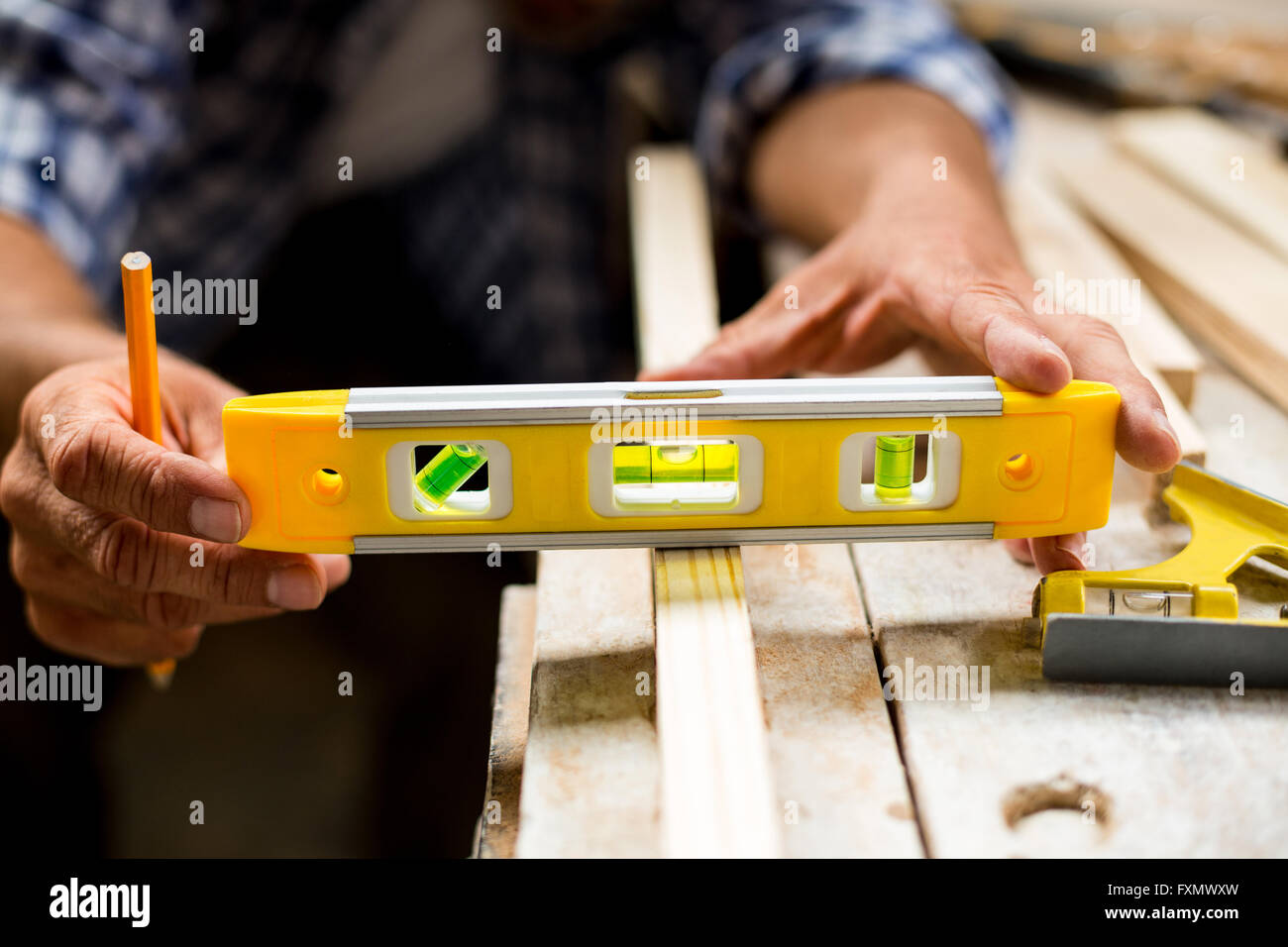 Carpenter measuring une longueur de planche en bois avec un niveau à bulle Banque D'Images