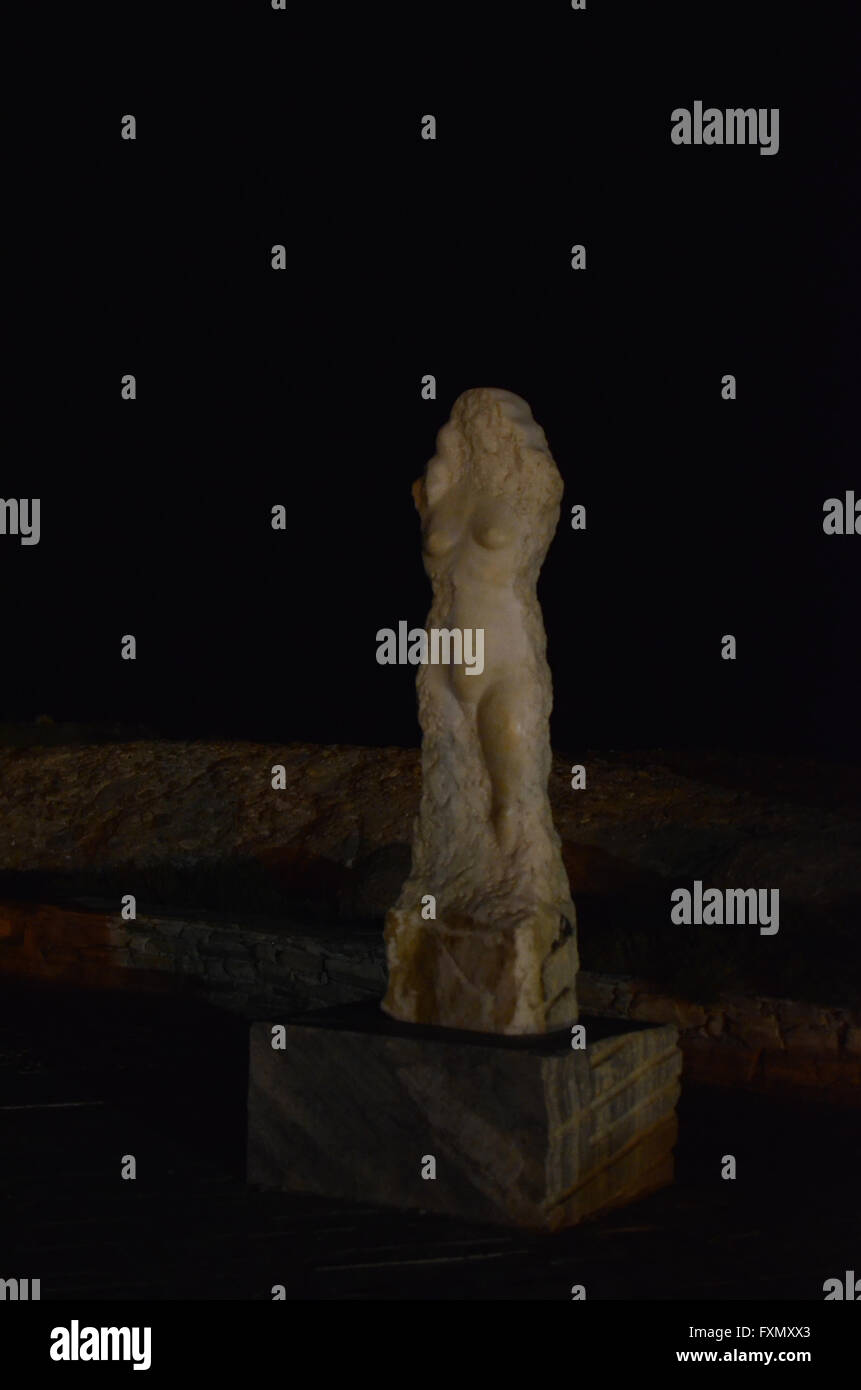 Vue de nuit sur une sculpture en marbre moderne (une forme féminine) sur le chemin sur le site archéologique d'Apollon appelé Portara . Banque D'Images