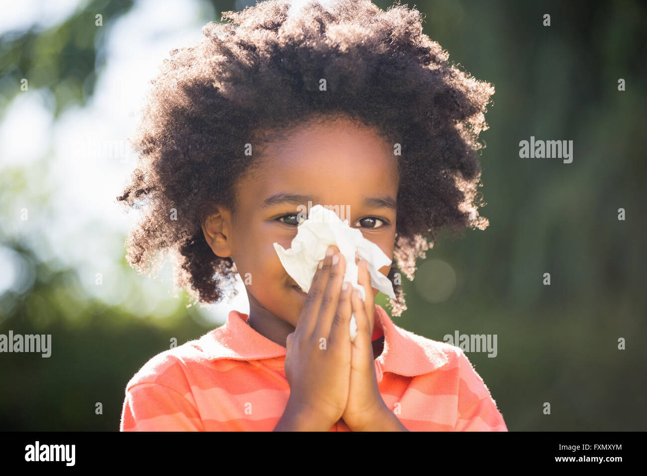 Enfant de race mixte soufflant son nez Banque D'Images