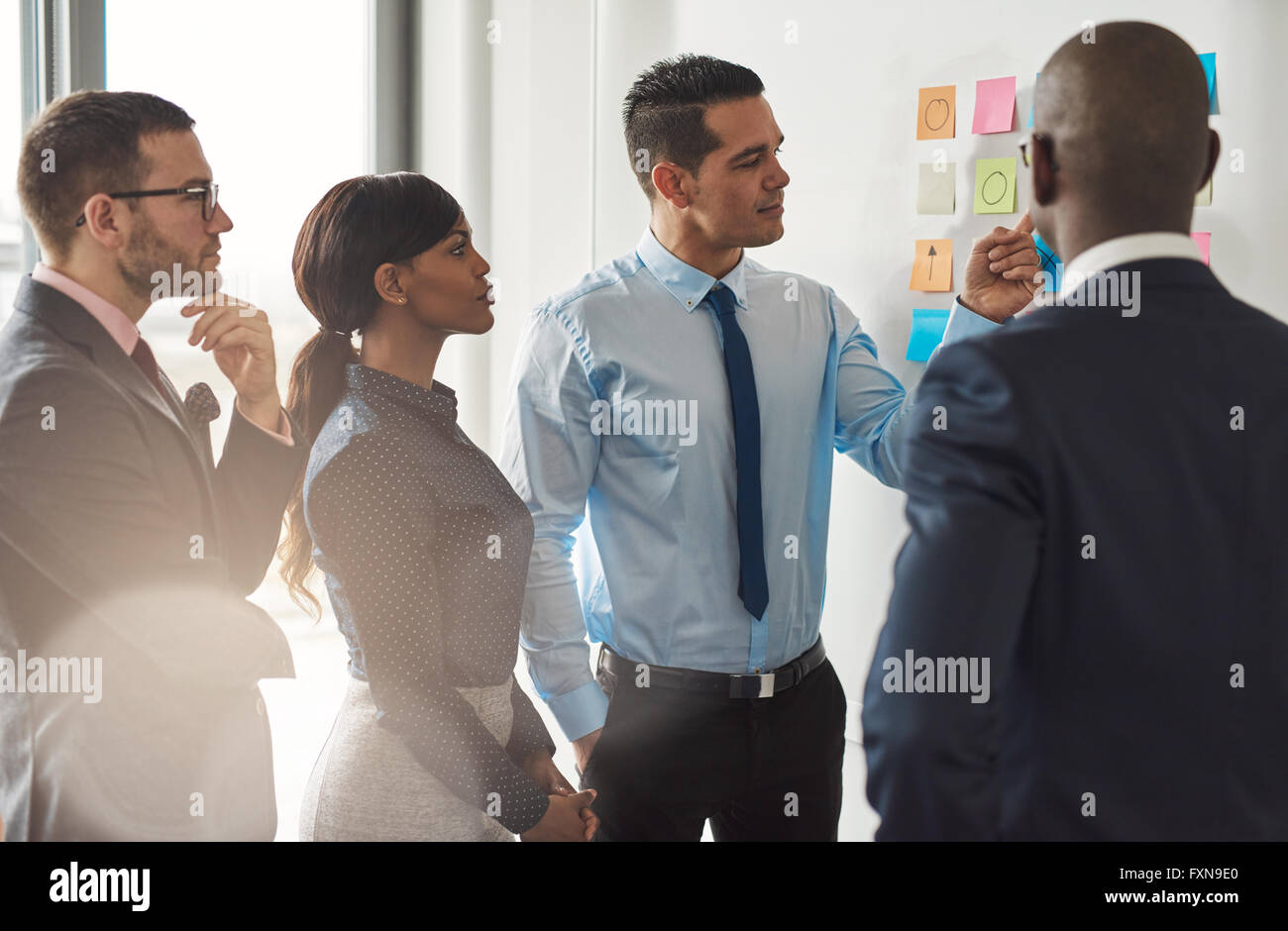 Groupe multiracial de businesspeople standing discuter des notes colorées sur un mur dans un concept d'équipe et coopération Banque D'Images