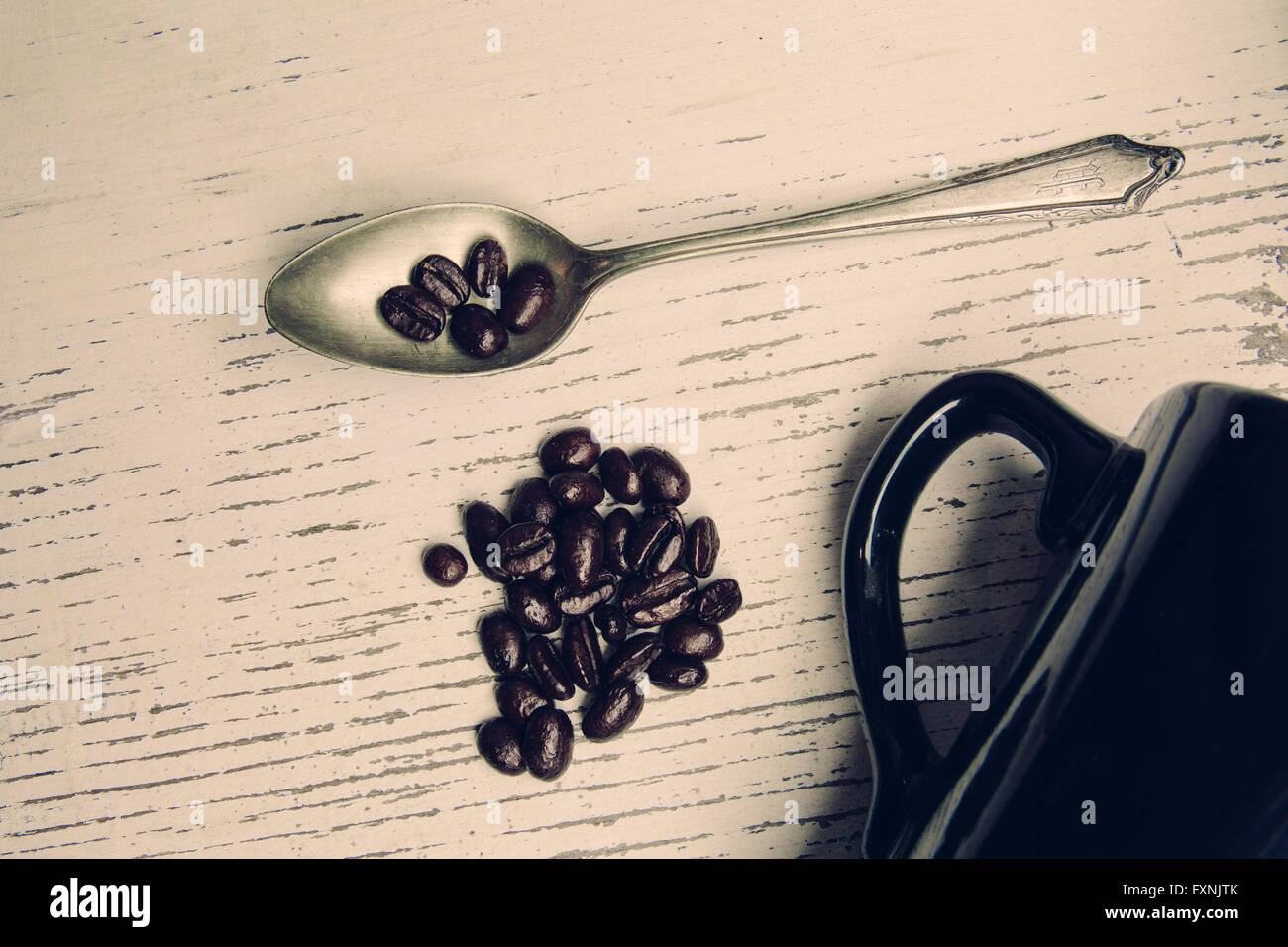 Cuillère vintage avec des grains de café et une tasse noire sur une table rustique tourné à partir de ci-dessus. Banque D'Images