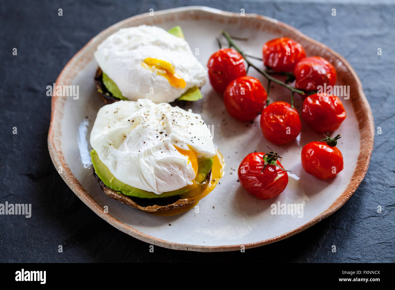 Le petit-déjeuner, les champignons avec de l'avocat et œufs pochés et faites rôtir les tomates cerise sur la vigne Banque D'Images