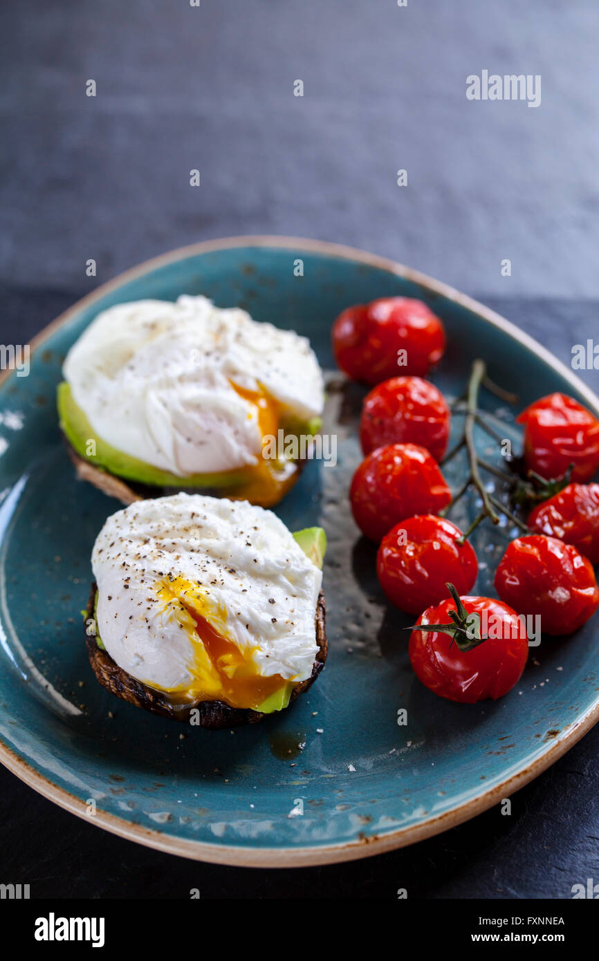 Le petit-déjeuner, les champignons avec de l'avocat et œufs pochés et faites rôtir les tomates cerise sur la vigne Banque D'Images