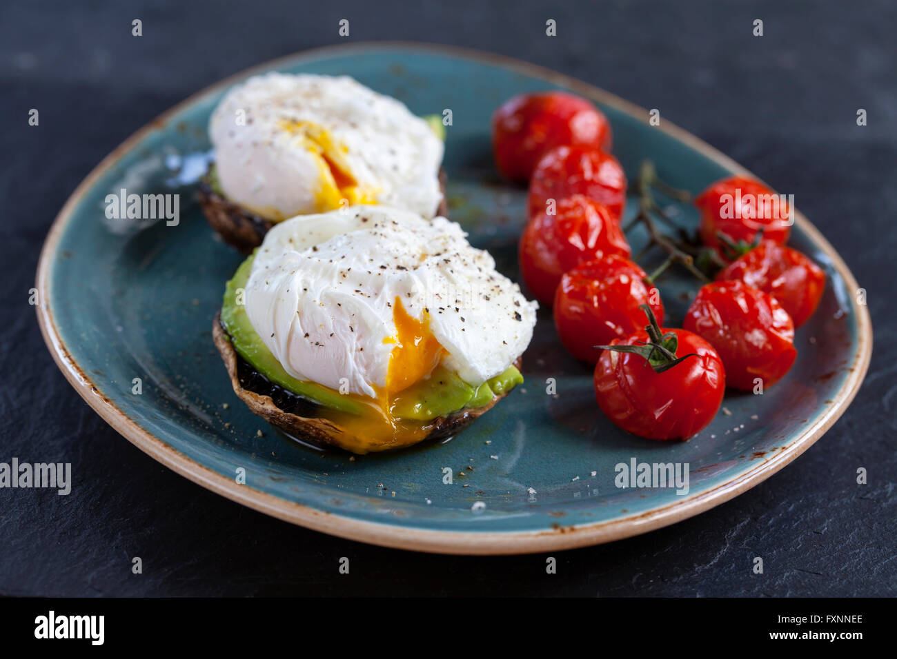 Le petit-déjeuner, les champignons avec de l'avocat et œufs pochés et faites rôtir les tomates cerise sur la vigne Banque D'Images