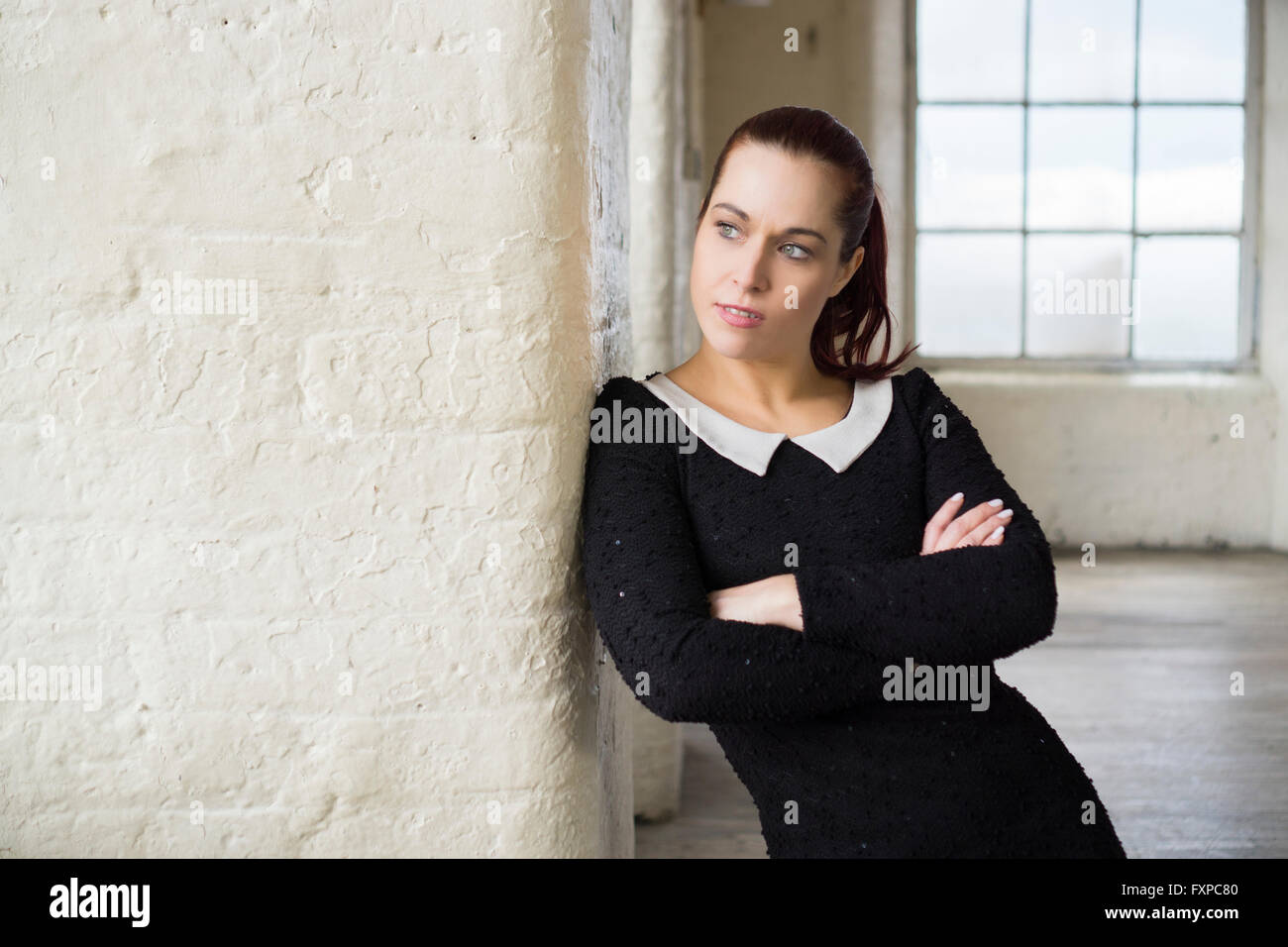 Femme bras croisés appuyé contre le mur à l'écart Banque D'Images