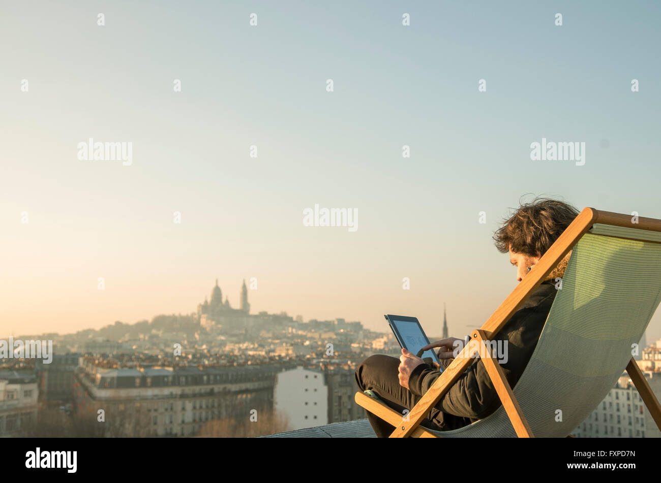 Man relaxing on toit-terrasse with digital tablet Banque D'Images