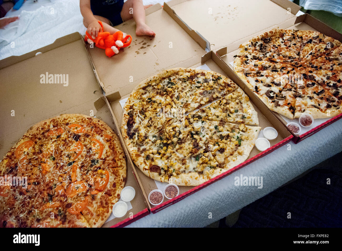 Enfant assis près de grandes pizzas en boîtes ouvertes Banque D'Images