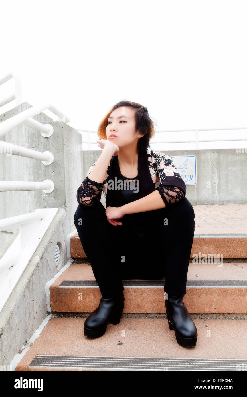 Moody Shot of Asian American Woman Sitting escalier extérieur Banque D'Images