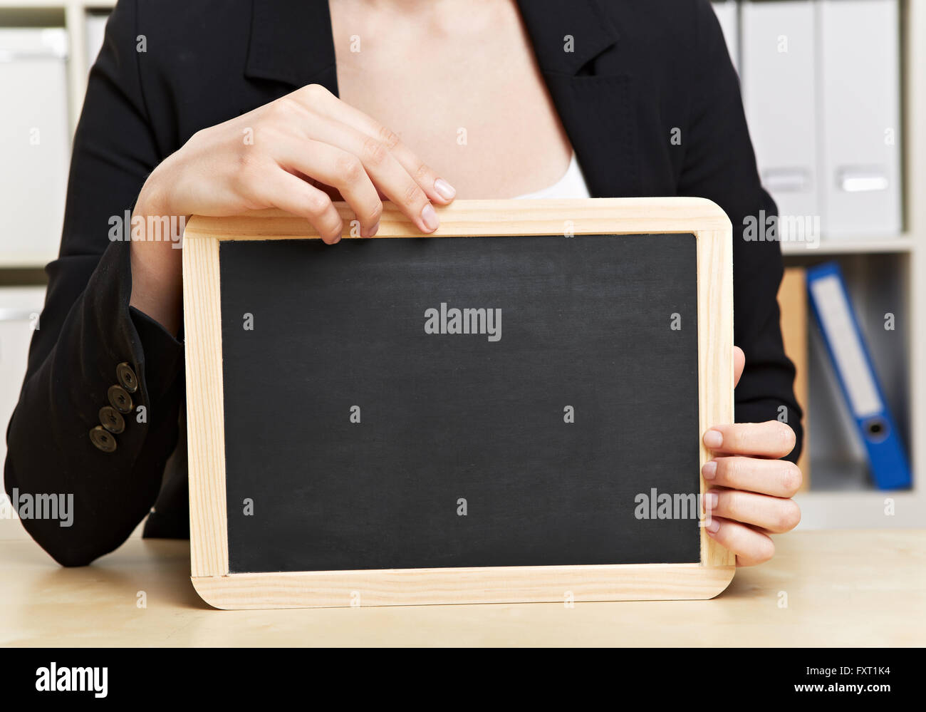 Mains tenant en ardoise noire vide tableau in office Banque D'Images