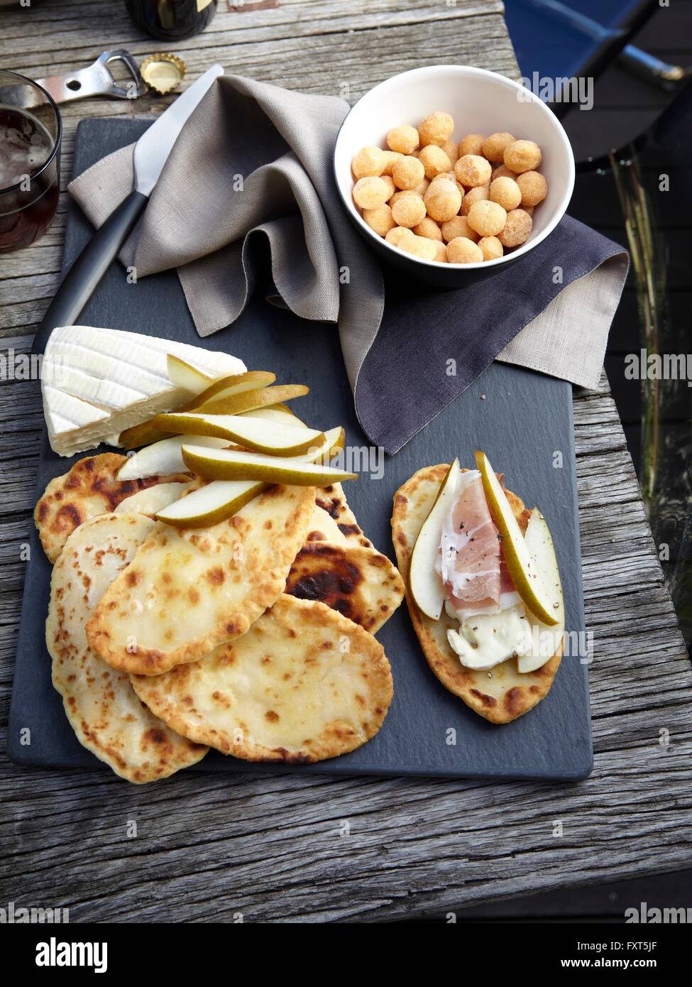 Vue de dessus de pains plats, tranches de poires, Taleggio, prosciutto et macadamias Banque D'Images