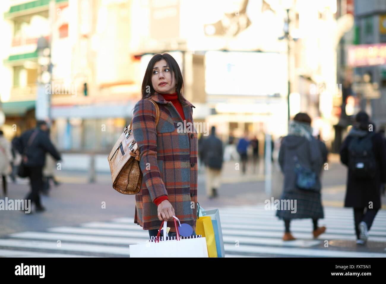 Side view of mature woman in city shopping à la voiture sur l'épaule, Shibuya, Tokyo, Japon Banque D'Images