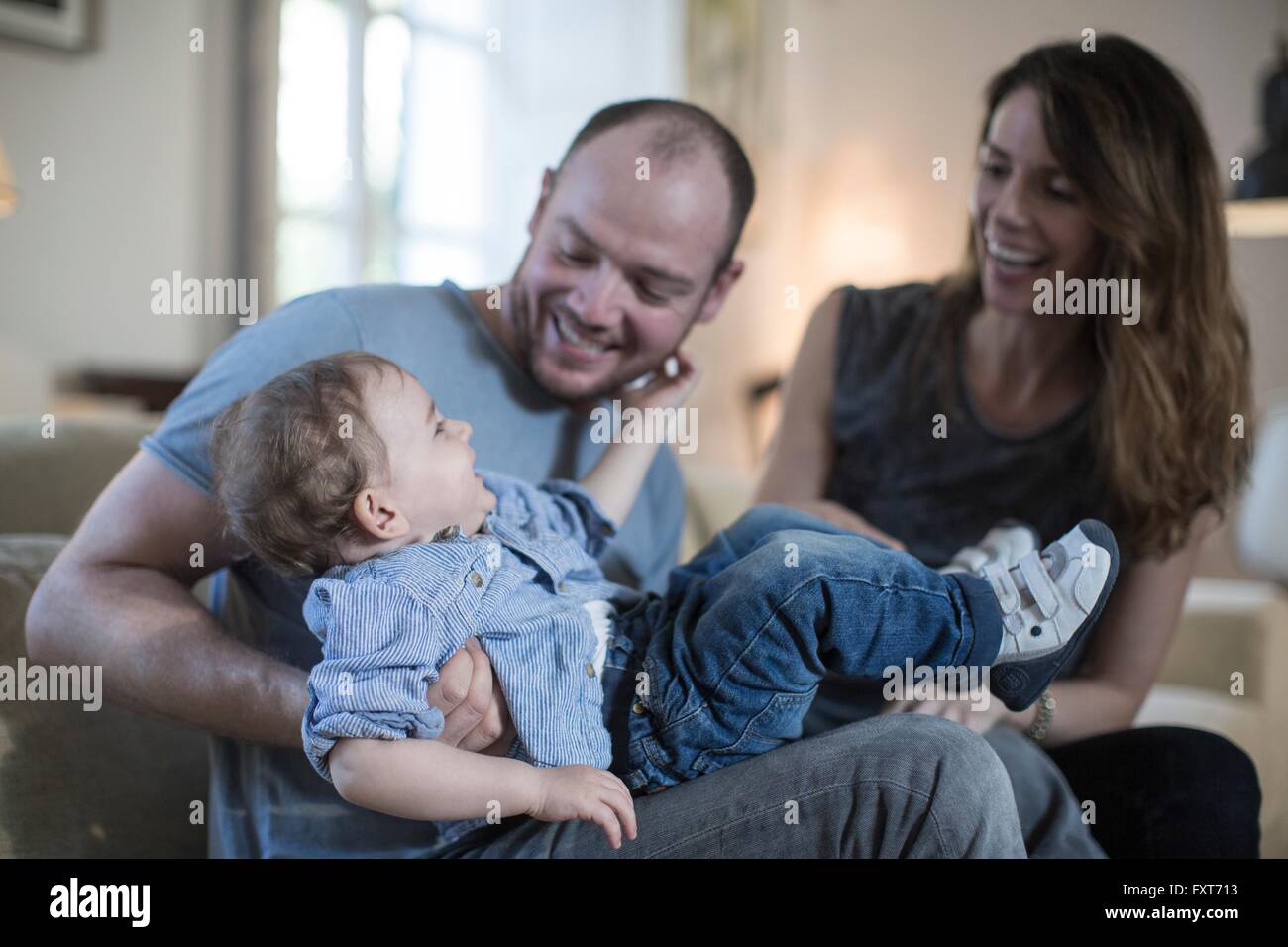 Les parents assis jouant avec smiling baby boy Banque D'Images