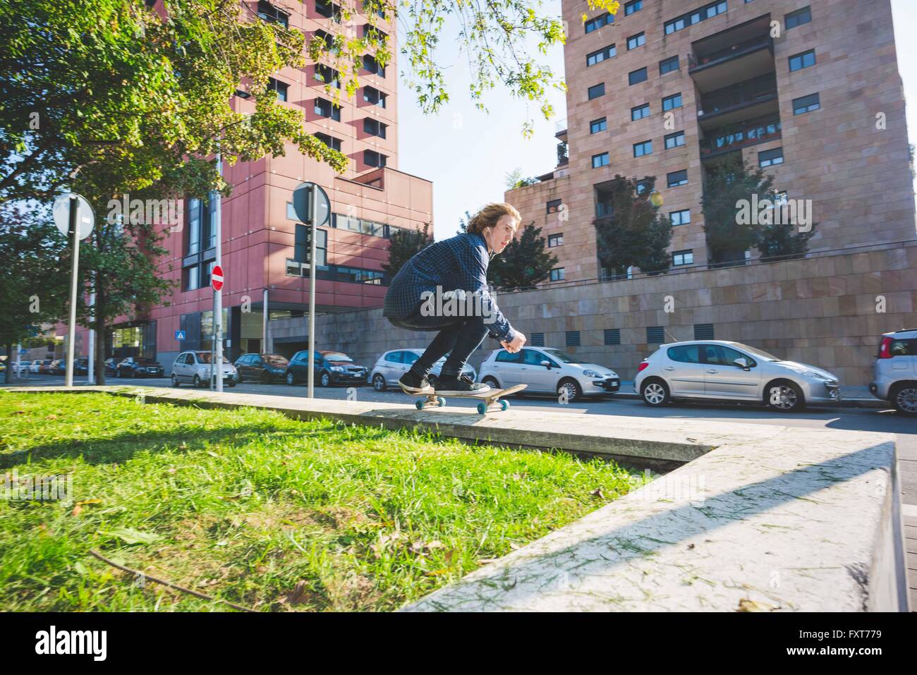 Jeune homme skate skateboarder sur mur urbain Banque D'Images
